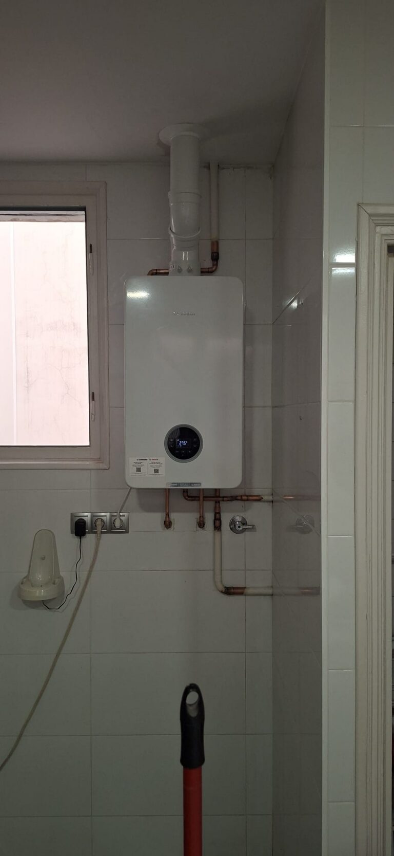 Caldera de condensación Junkers Bosch instalada por JAG Alcaide en una cocina, con salida de humos vertical