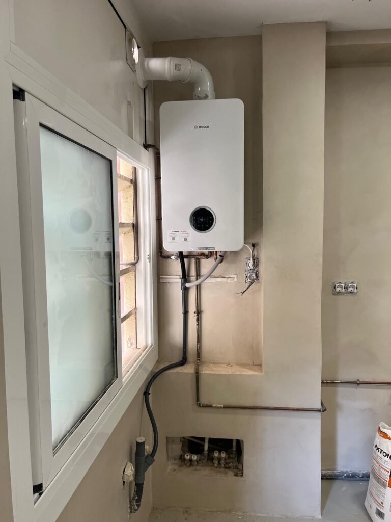 Caldera de condensación Junkers Bosch instalada por JAG Alcaide en una galería en reforma, con salida de humos a fachada