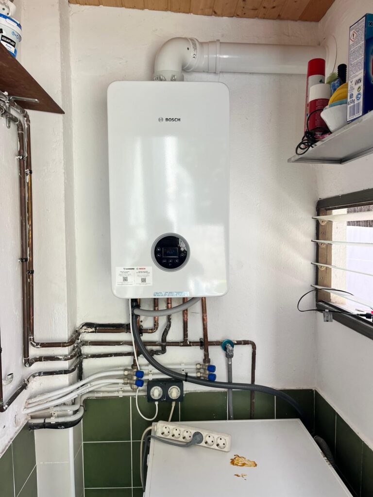 Caldera de condensación Junkers Bosch instalada por JAG Alcaide en un lavadero, con salida de humos horizontal